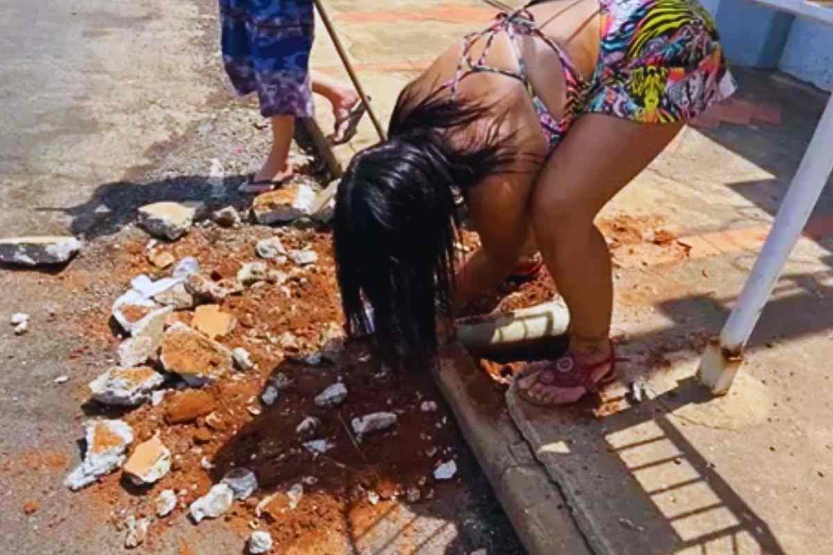 Una ragazza cerca di tirare fuori un gatto dalla tubatura